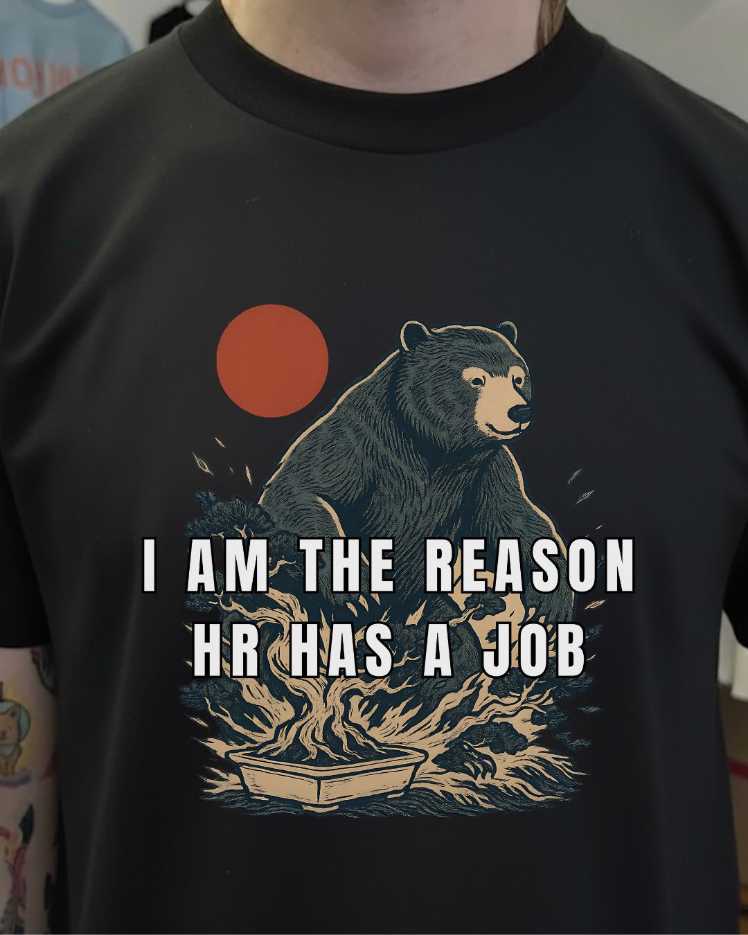 Black t-shirt with bear graphic and text 'I AM THE REASON HR HAS A JOB' on a plain background