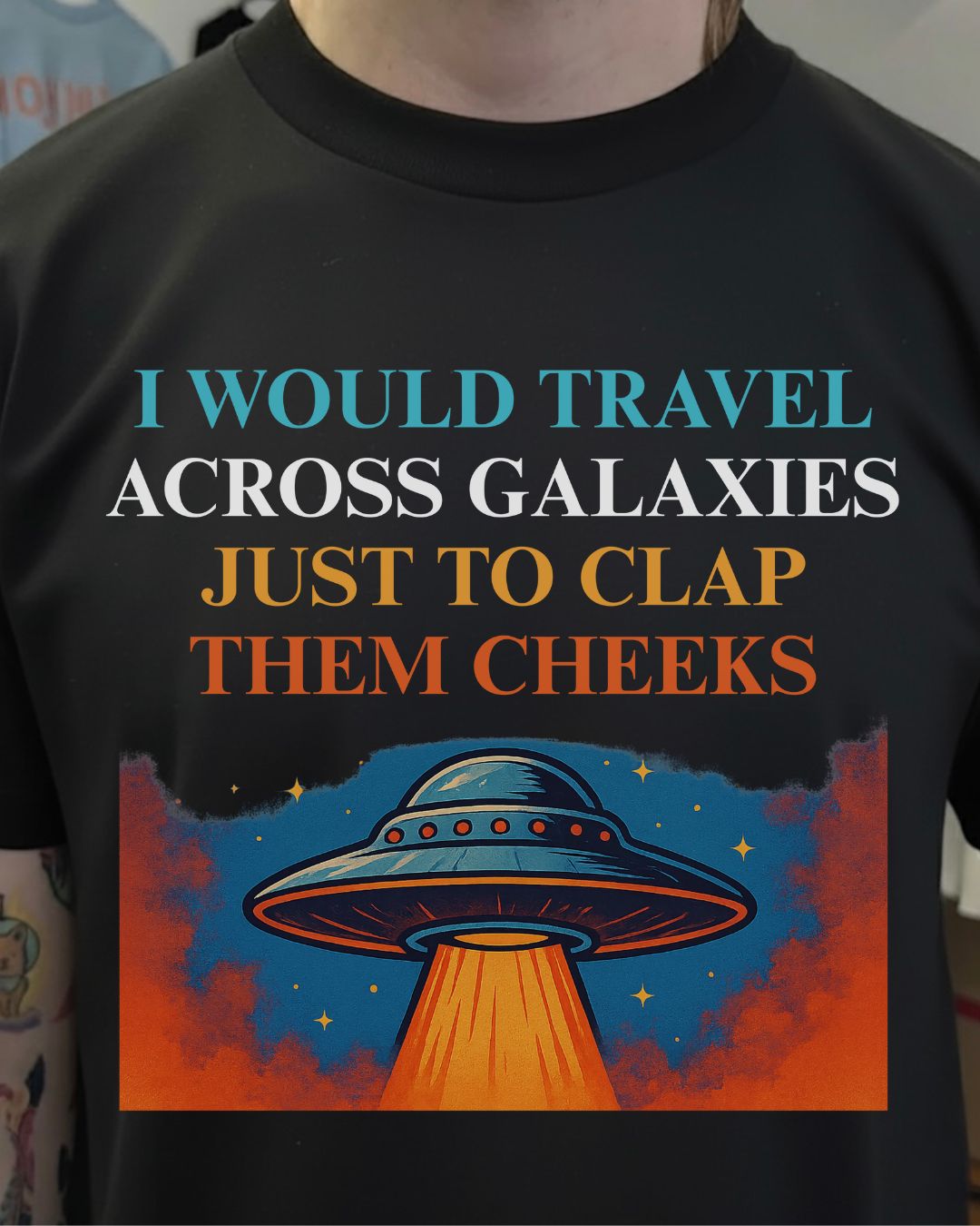 Black t-shirt with a UFO design and humorous text about traveling across galaxies.