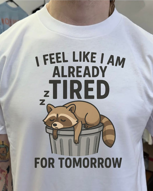 White t-shirt with a raccoon graphic and text on a plain background